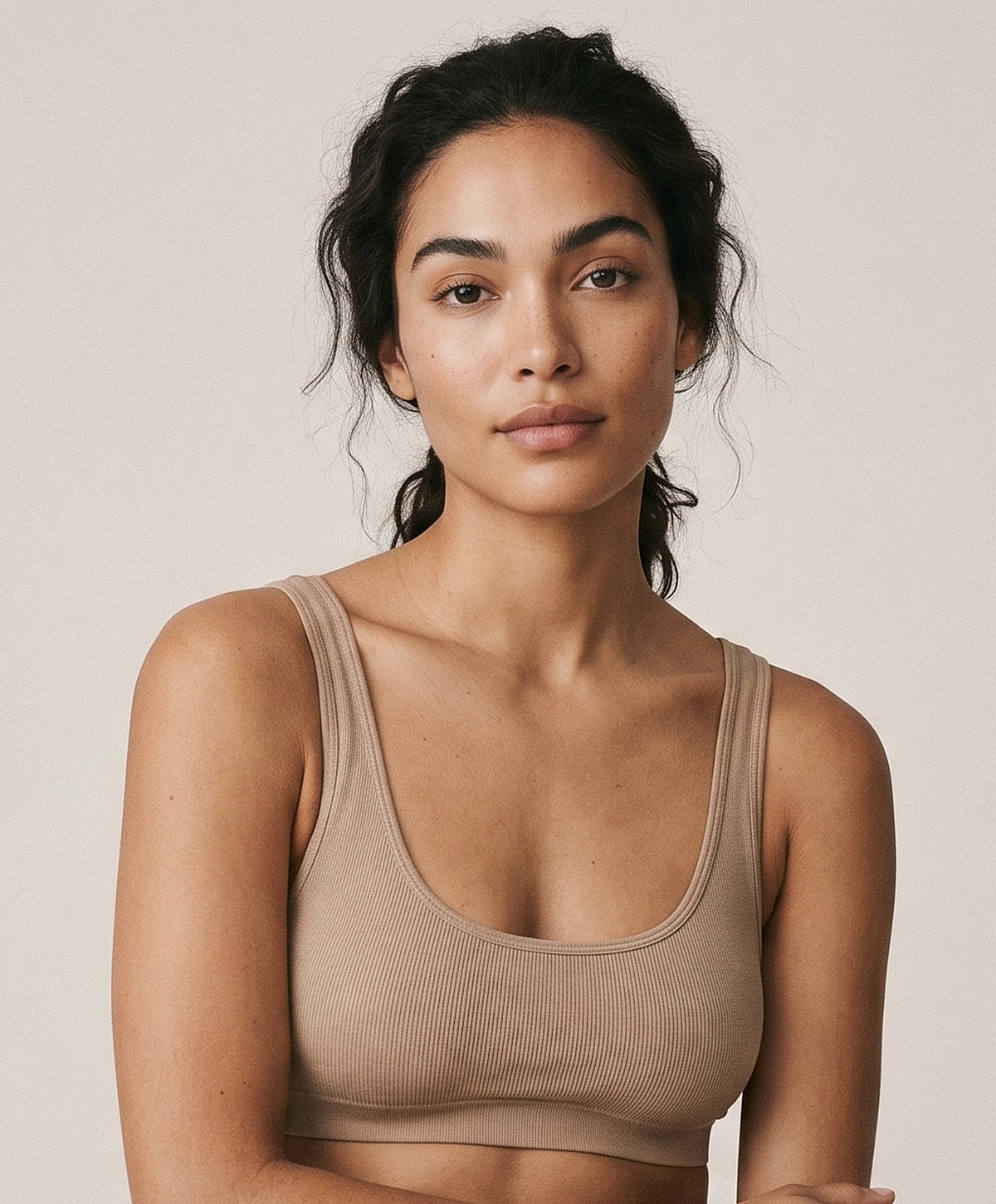 Young woman wearing a beige ribbed top.