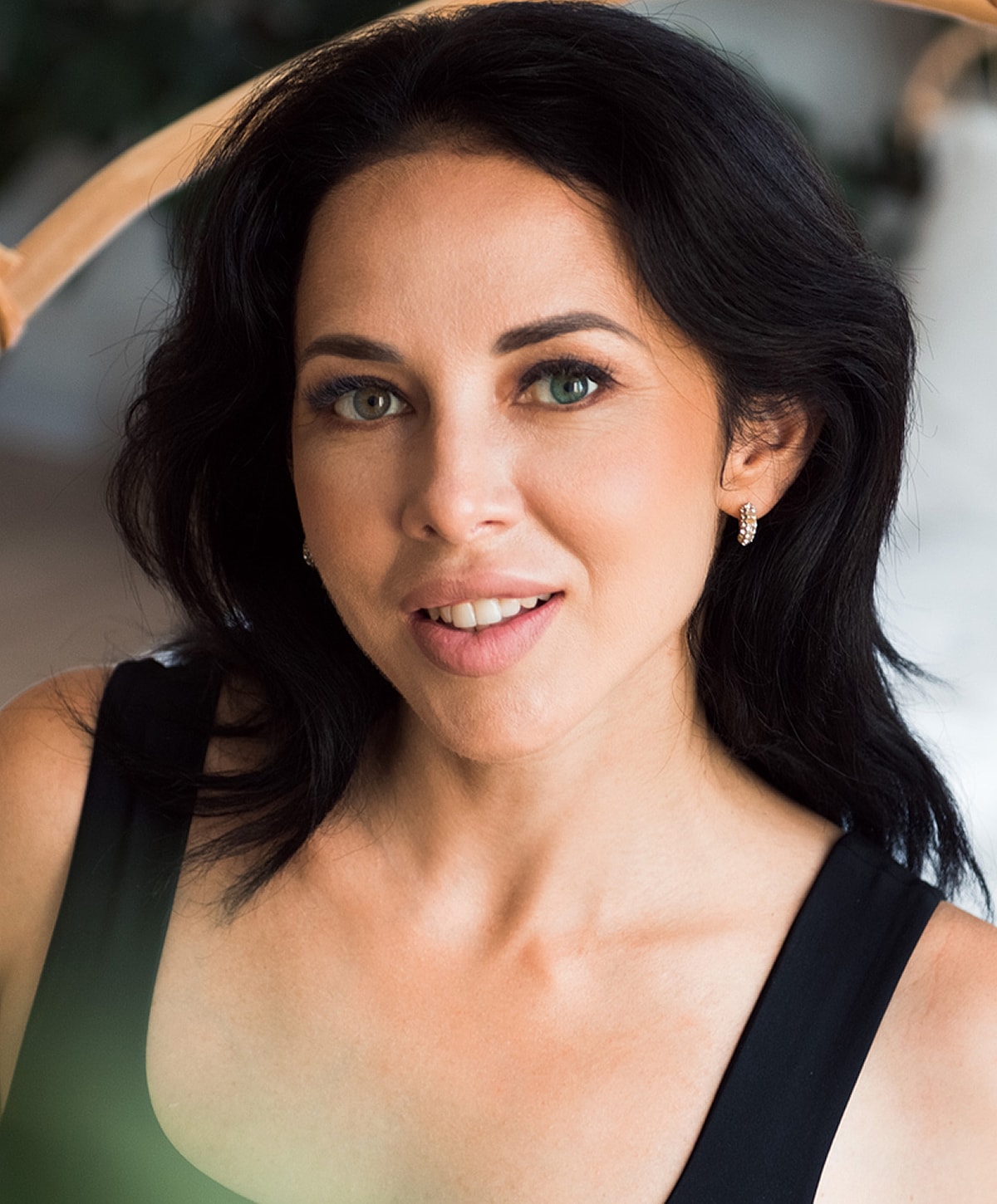 Smiling woman with dark hair and earrings.