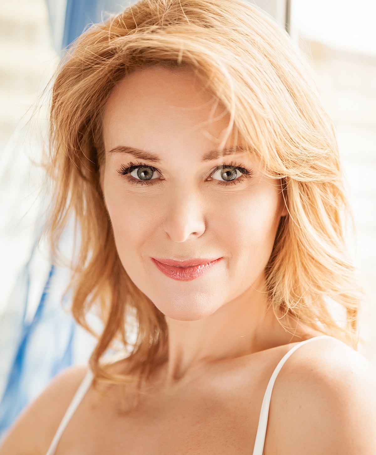 Smiling woman with blonde hair and blue eyes.