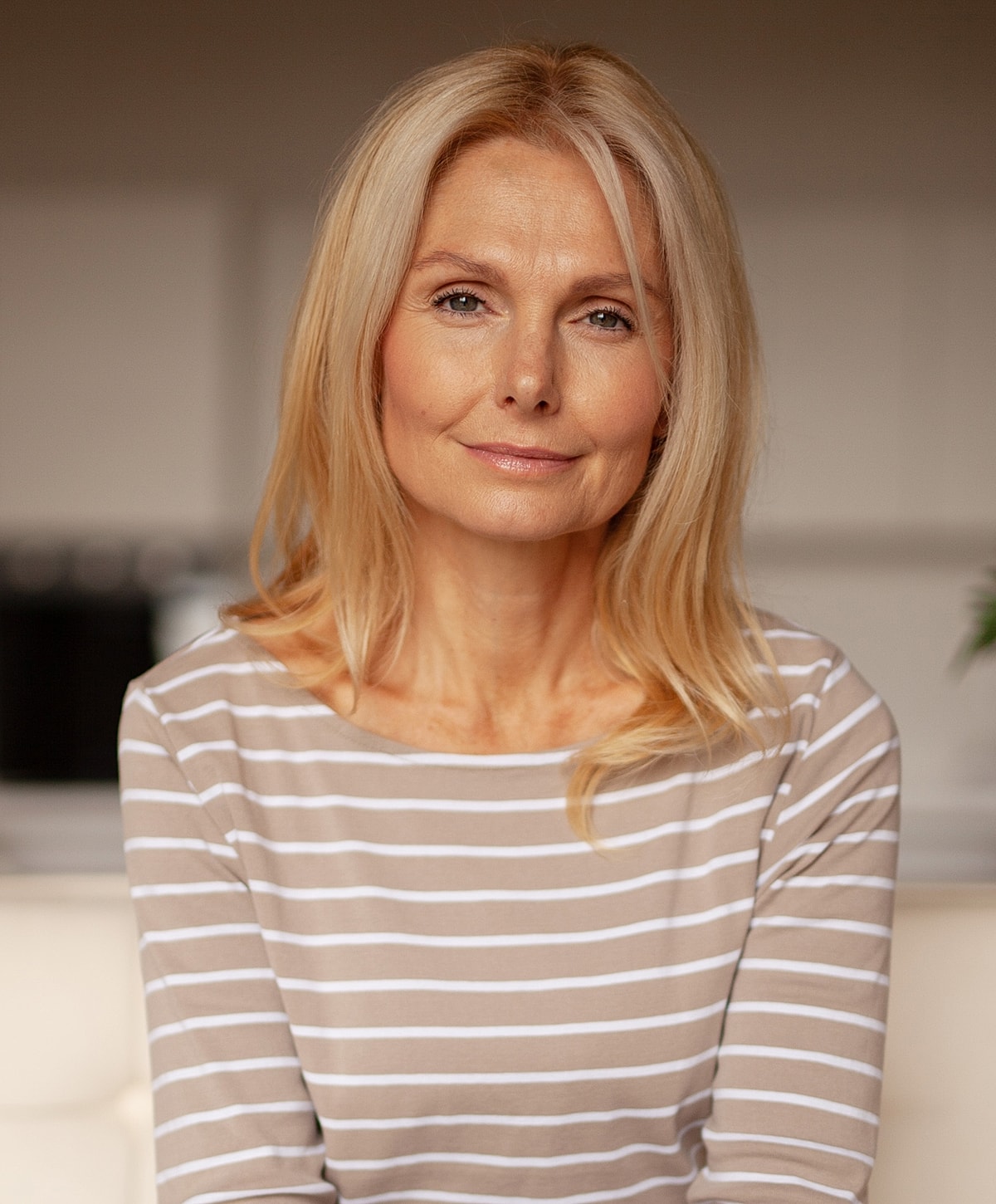 Smiling woman with long blonde hair indoors.