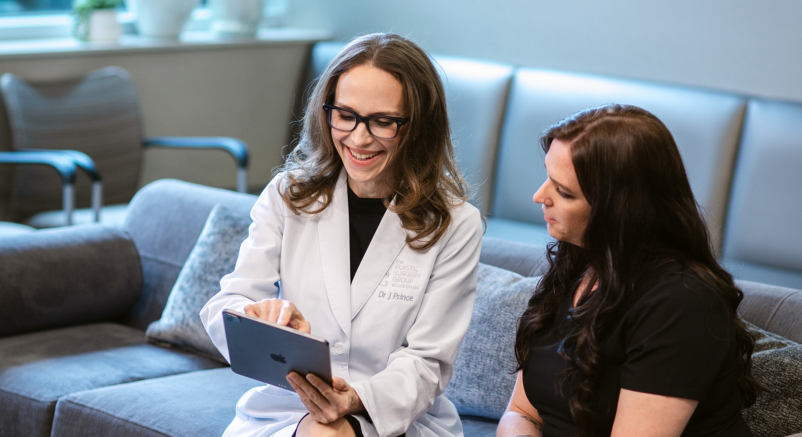 Three women in medical scrubs smiling together.