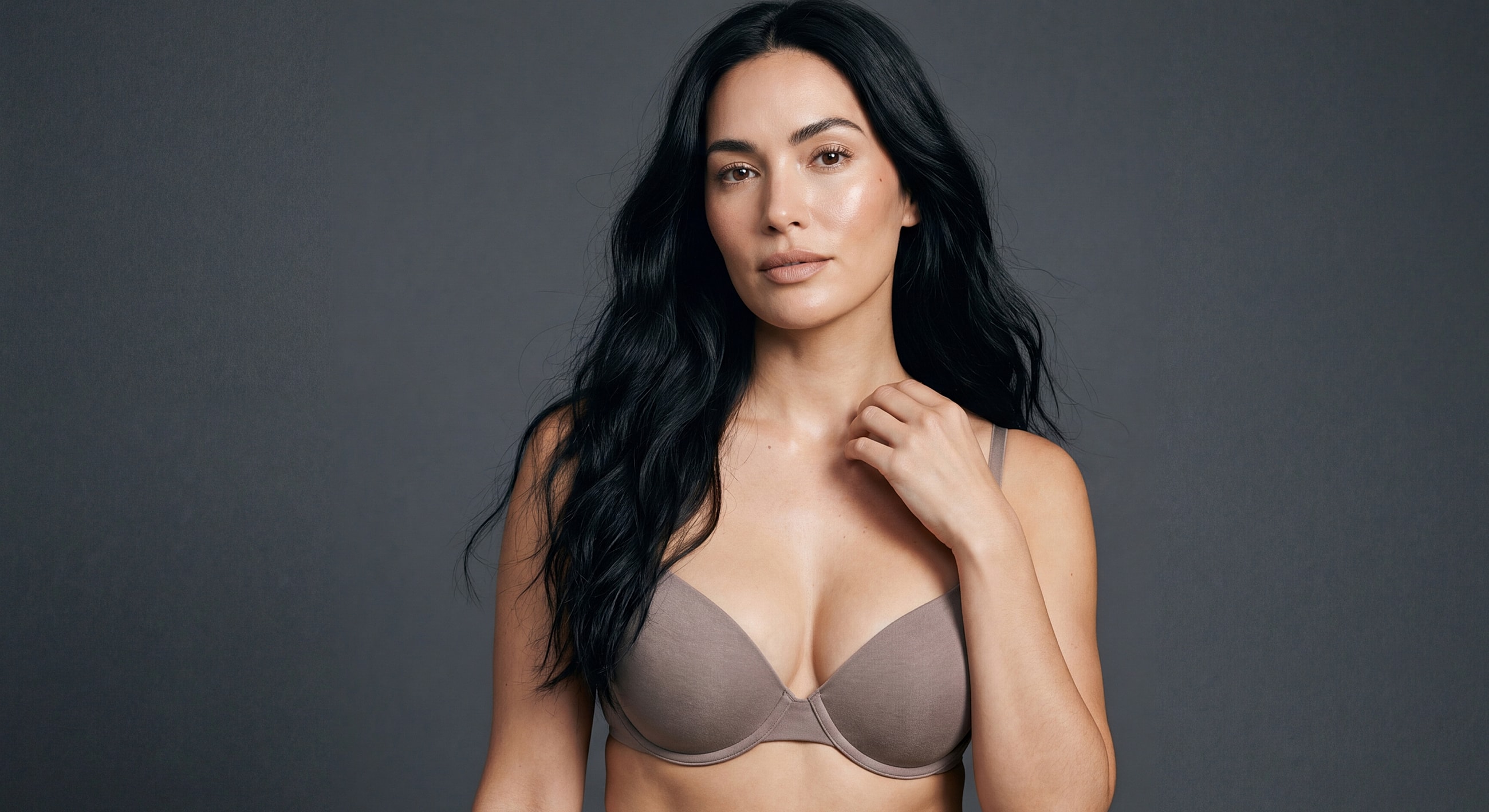 Model posing in a bra against gray background.